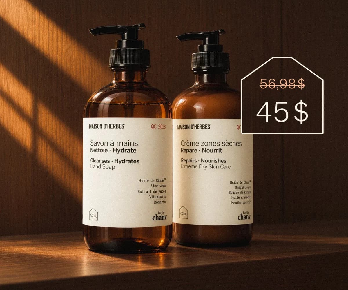 Le Savon à mains et la Crème zones sèches Maison d’Herbes côte à côte sur une tablette de bois, dans un rai de lumière chaude, avec une étiquette de prix : 56,98 $ barré, 45 $